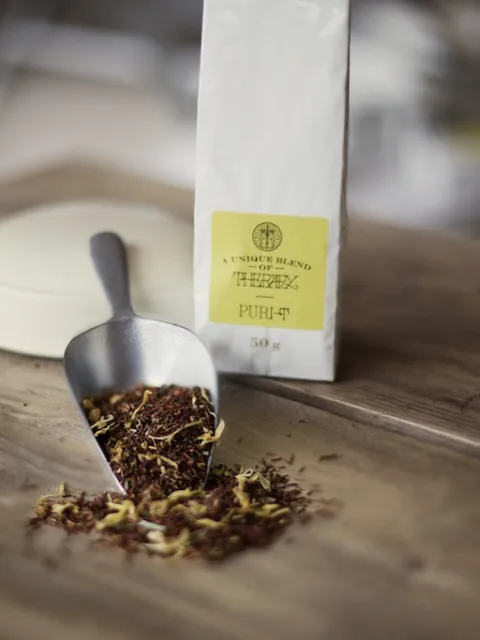 Tea blend with scoop on wooden table, labelled "Purity" 50g.