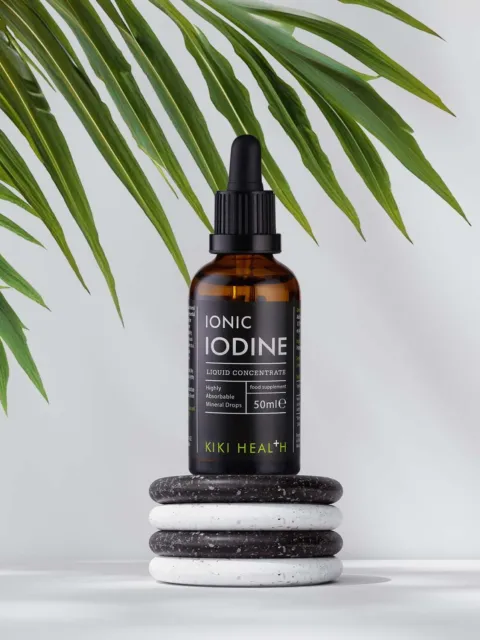 Brown bottle of Ionic Iodine on stacked stones, with green leaves in the background.