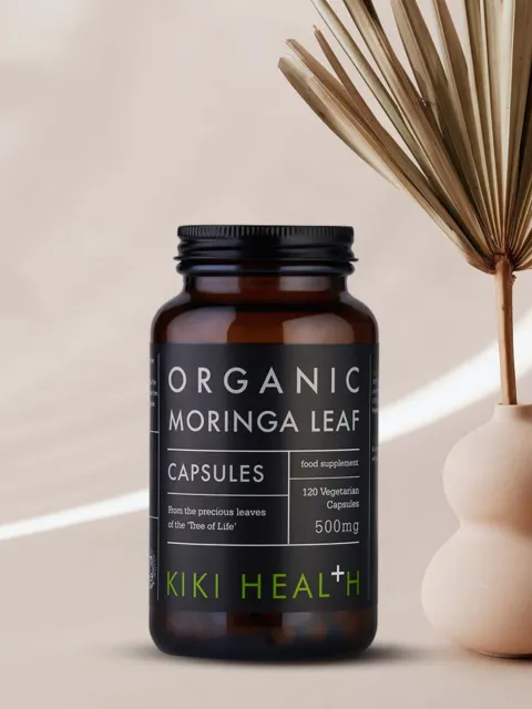 Organic Moringa Leaf capsules, 120 vegetarian, 500mg, by Kiki Health, next to a dried plant.