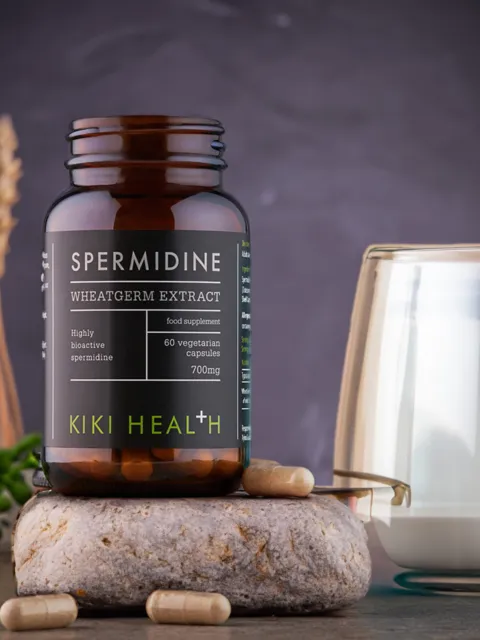 Spermidine wheatgerm extract bottle with capsules, glass of milk, and wheat stalks.