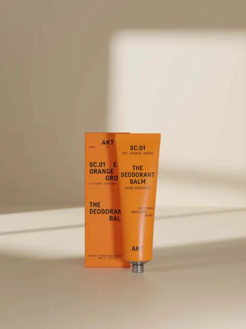 Orange deodorant balm tube and box with text "SC.01 EXT. ORANGE GROVE".