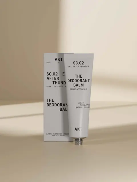 AKT SC.02 After Thunder deodorant balm tube and box on a beige surface.