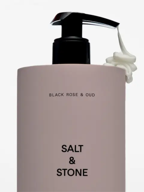 Salt & Stone bottle with pump, text: Black Rose & Oud. Cream dispensed from nozzle.