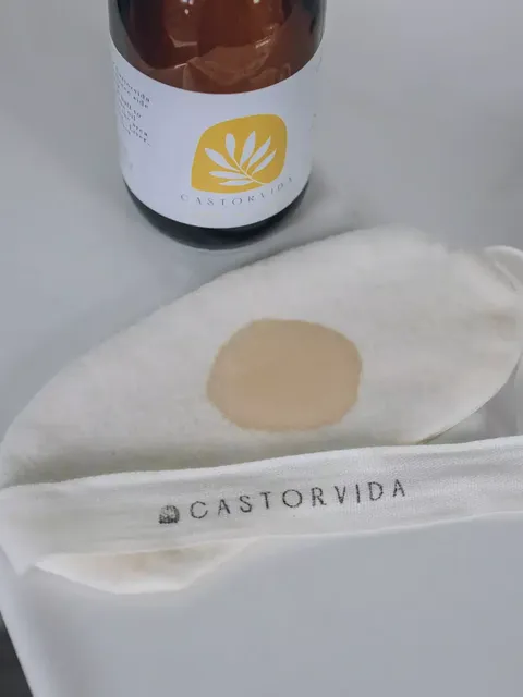 Bottle with Castorvida label and a fabric pad with a stain on a white surface.