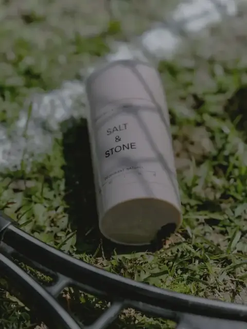 Salt & Stone deodorant on grass beside a tennis racket and ball.