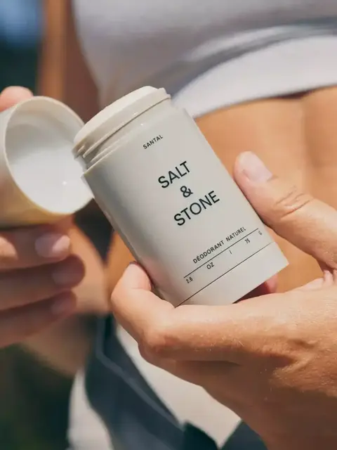 Person holding Salt & Stone deodorant stick with cap off.