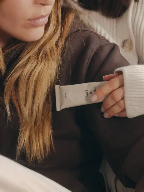 Person holding a tube labelled "Salt & Vine" against a brown jumper.