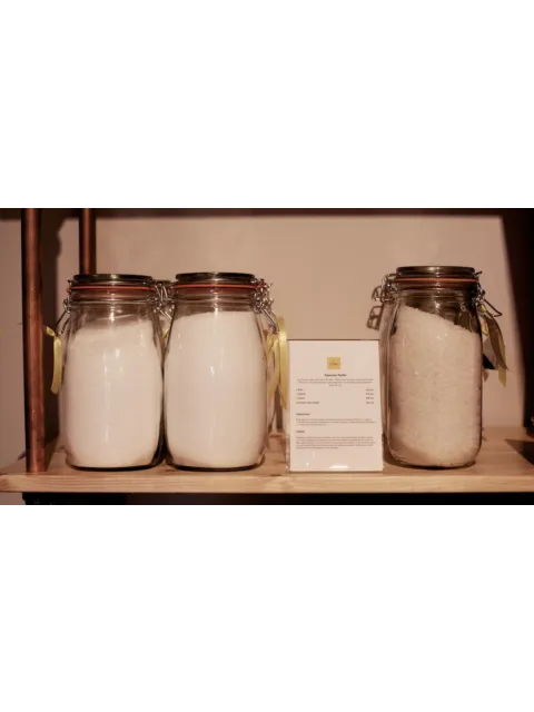 Three jars of Epsom salts on a wooden shelf with a product description card.