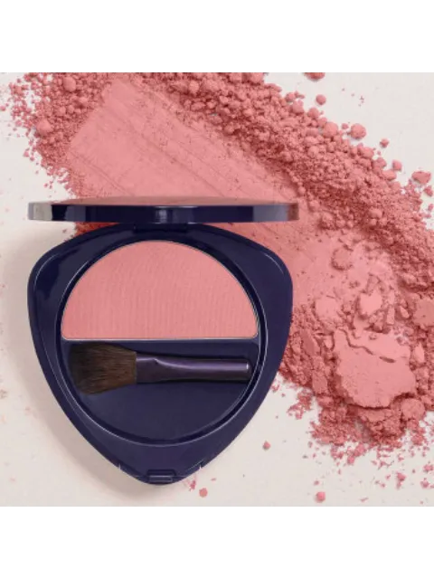 Pink blush compact with brush, surrounded by loose powder on a light background.