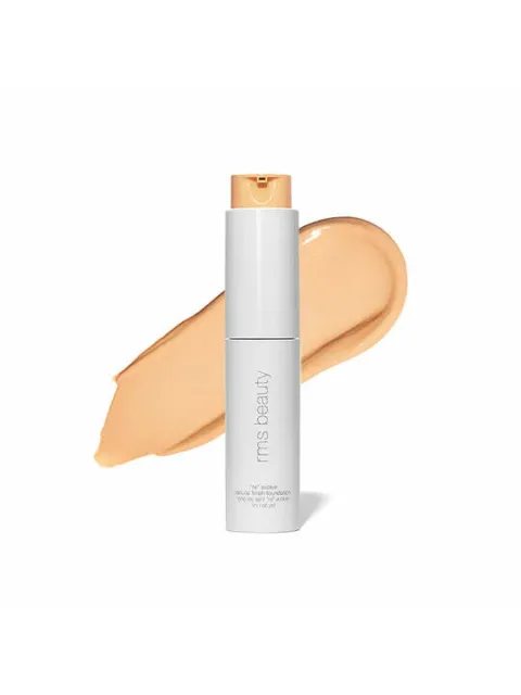 White bottle of RMS Beauty foundation with beige swatch behind.