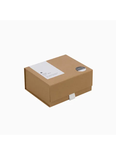 Brown gift box with white label and round black sticker on the lid.