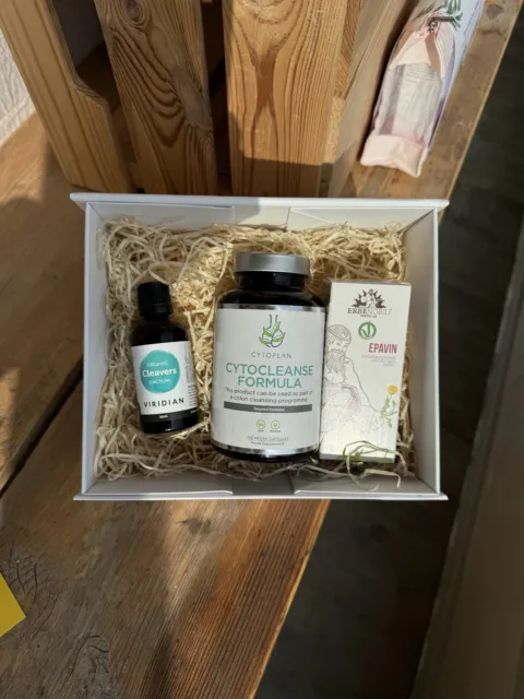Cleansing products in a white box on a wooden surface, including CytoCleanse Formula and Cleavers Tincture.