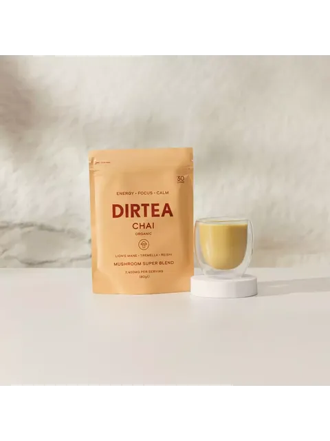 DIRTEA Chai organic mushroom blend pouch and glass cup on a white surface.