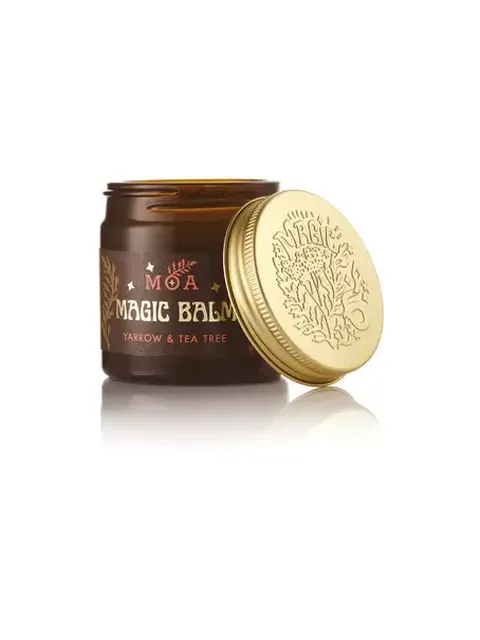 Brown jar of MOA Magic Balm, yarrow and tea tree, with a gold lid beside it.