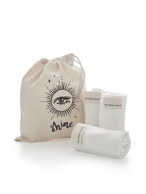 Drawstring bag with eye design and "shine" text, three rolled cloths labelled "The Green Balm".