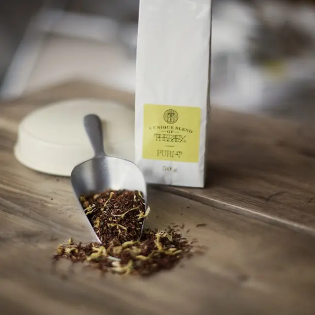 Tea blend with scoop on wooden table, labelled "Purity" 50g.