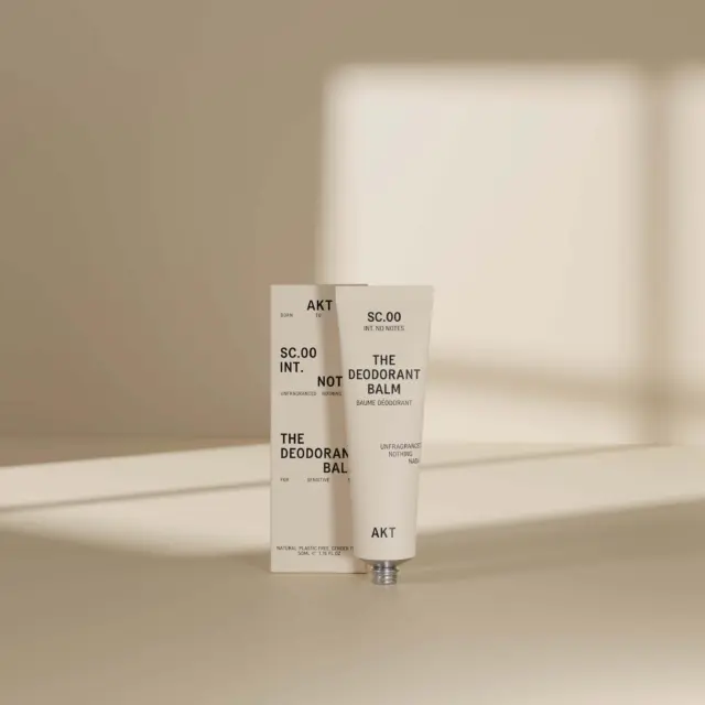 Deodorant balm tube and box with text, set against a neutral background.