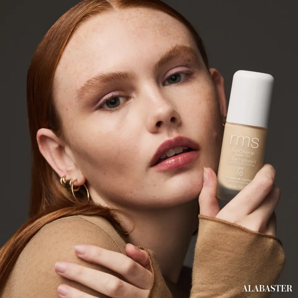 Person holding RMS Beauty foundation bottle, labelled "Alabaster".