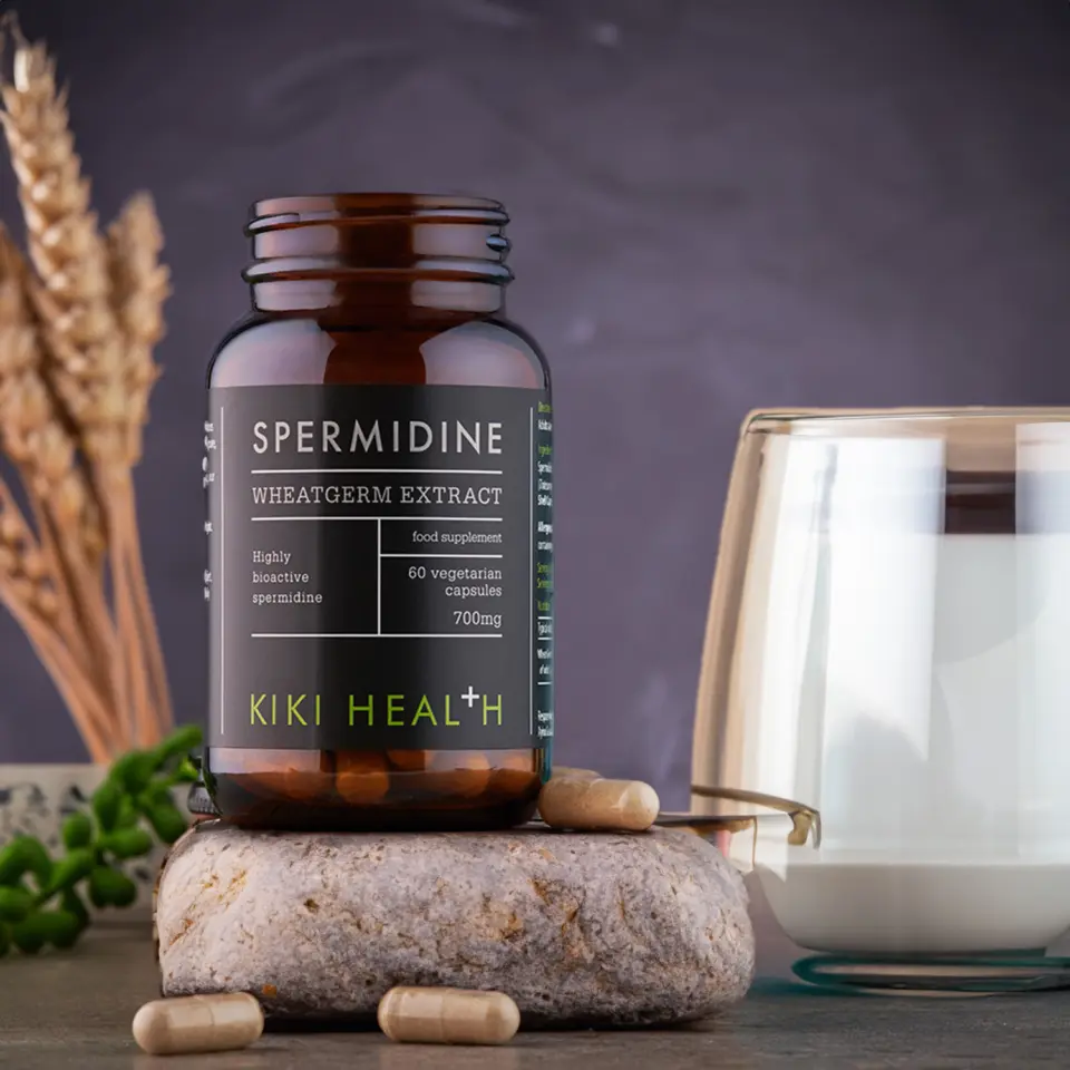 Spermidine wheatgerm extract bottle with capsules, glass of milk, and wheat stalks.