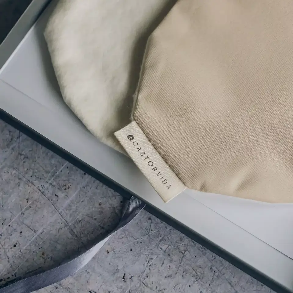 Beige and cream fabric bags with "CASTORVIDA" label in a box on a textured surface.