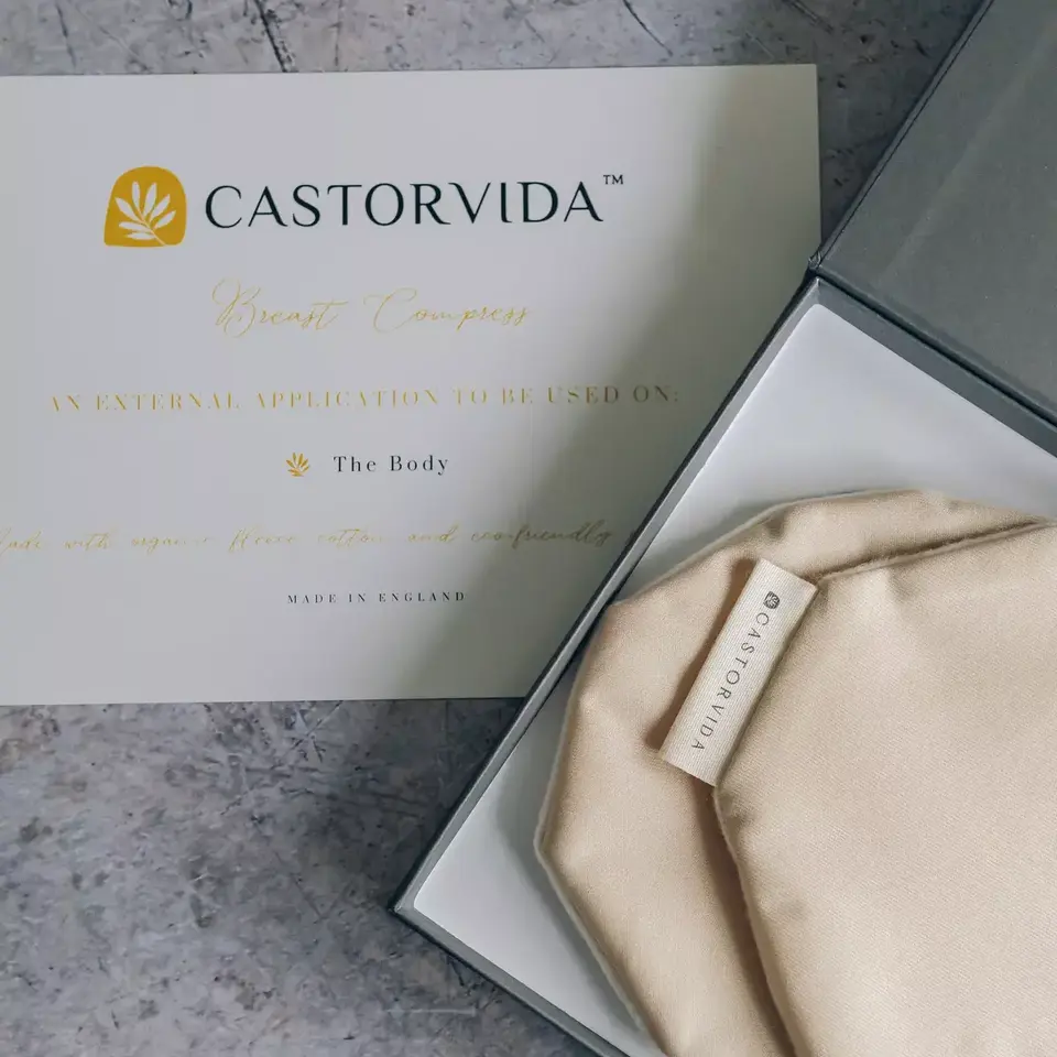 Castorvida breast compress with label in box, card with instructions on stone surface.