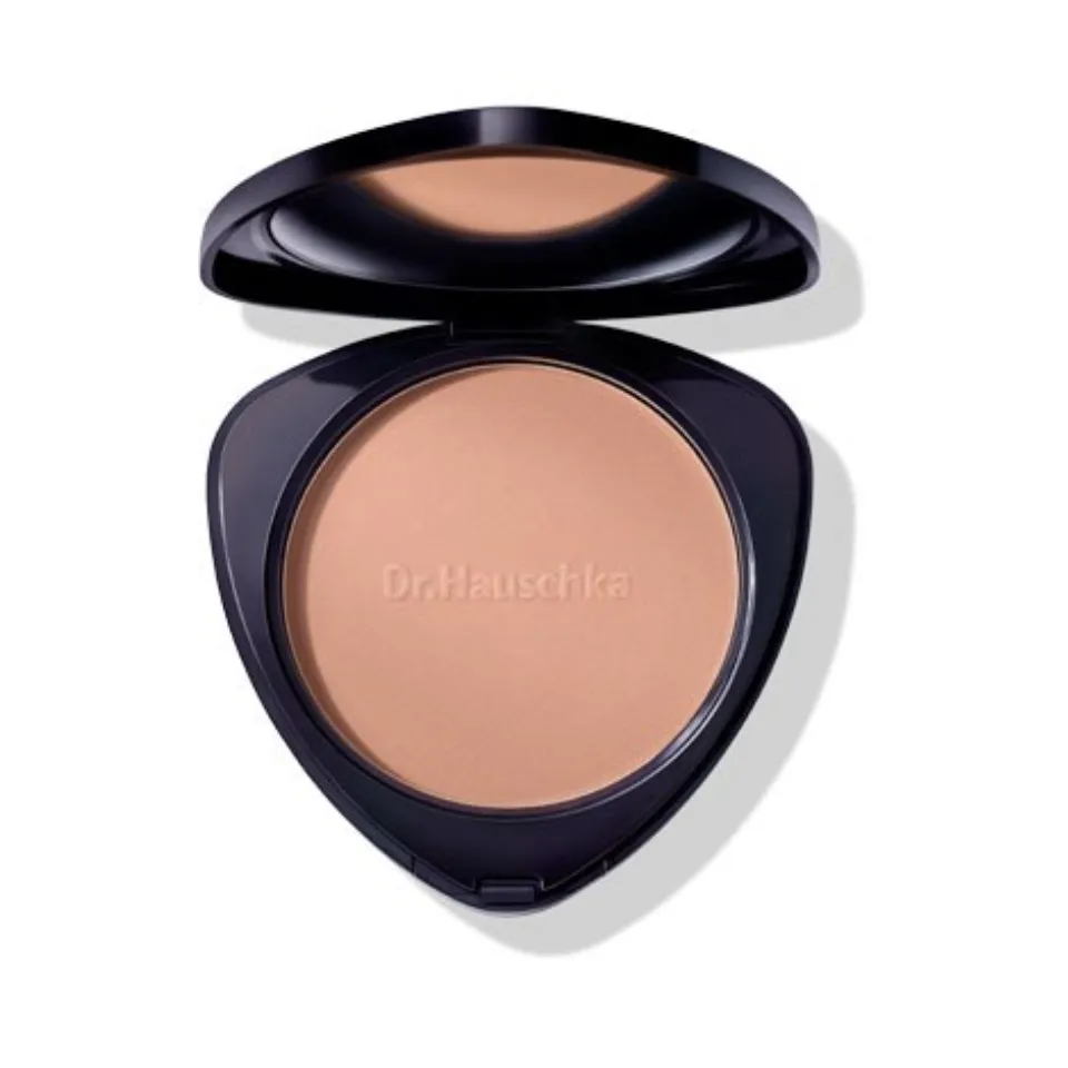 Compact powder with "Dr. Hauschka" embossed, in a black case with open lid.