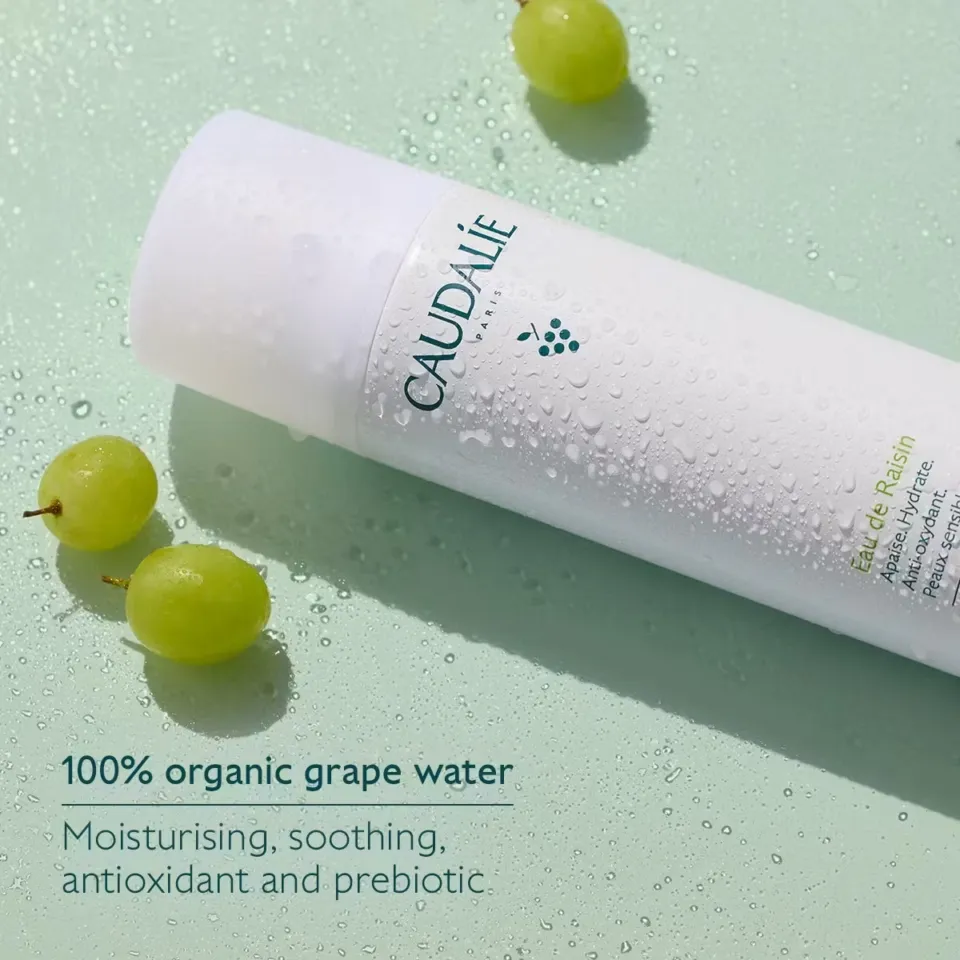 Caudalie grape water bottle with droplets, green grapes, and text on benefits.