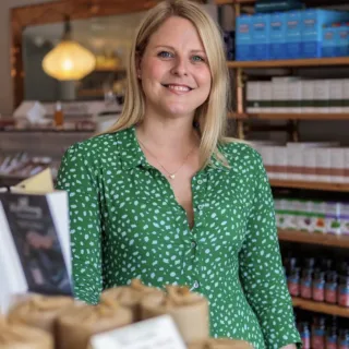 Woman in green blouse in a skincare shop with shelves of products in the background.
