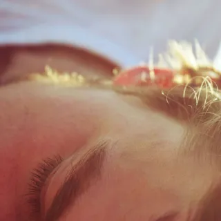 Close-up of a person's face lying down, focusing on the forehead and closed eye.