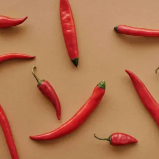 Red chillies scattered on a brown surface.