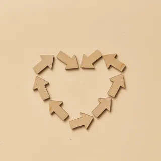Cardboard arrows arranged in a heart shape on a beige background.