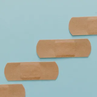 Four adhesive plasters arranged diagonally on a light blue background.