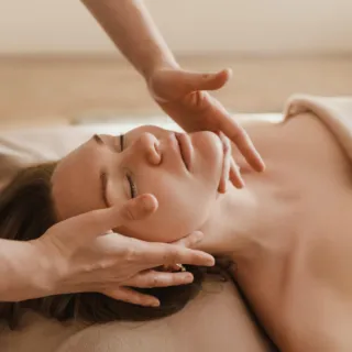 Person receiving a facial massage on a massage table.