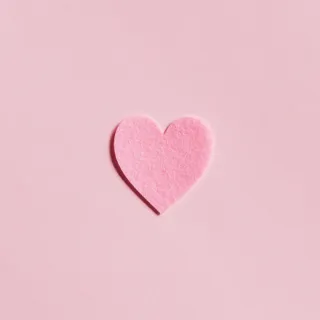 Pink felt heart on a matching pink background.