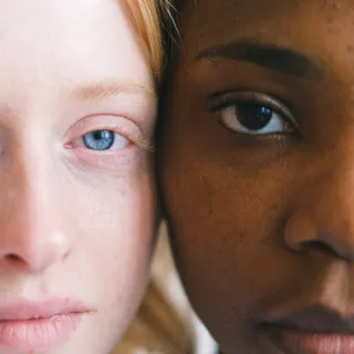 Two people with different skin tones, close-up of their faces side by side.