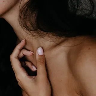 Person touching their neck with manicured nails.