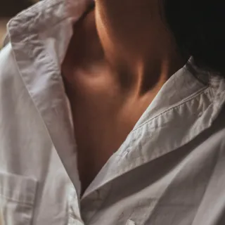 Person wearing a white shirt, showing neck and collarbone.