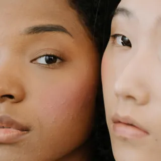 Two women with different skin tones, close-up of faces, neutral expressions.