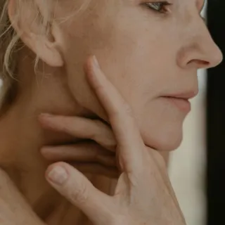 Person touching their face, focusing on skin texture and tone.