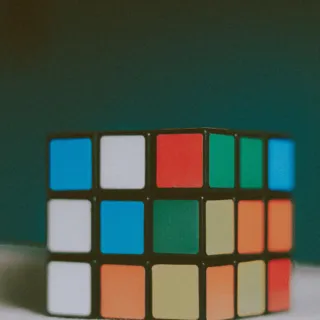 Rubik's Cube with mixed colours on a white surface against a dark background.