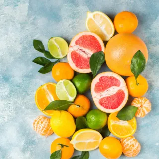 Assorted citrus fruits on a blue background, including grapefruit, lemon, lime, and oranges.