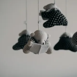 Hanging plush bears in monochrome patterns on strings against a plain background.