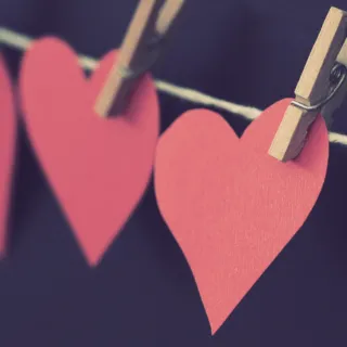 Red paper hearts clipped to a string with wooden pegs.
