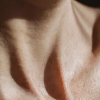 Close-up of a person's neck and collarbone with natural skin texture.