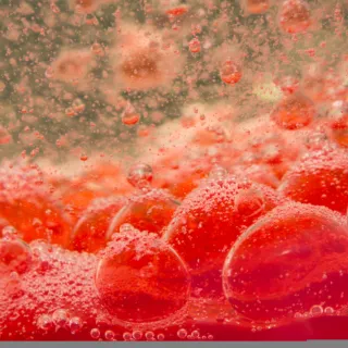 Red liquid with bubbles rising, creating a fizzy texture.