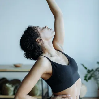 Person in black sportswear doing a yoga pose indoors.