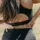 Woman in black sportswear holding her lower back outdoors.