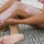 Person applying lotion to leg on patterned mat.