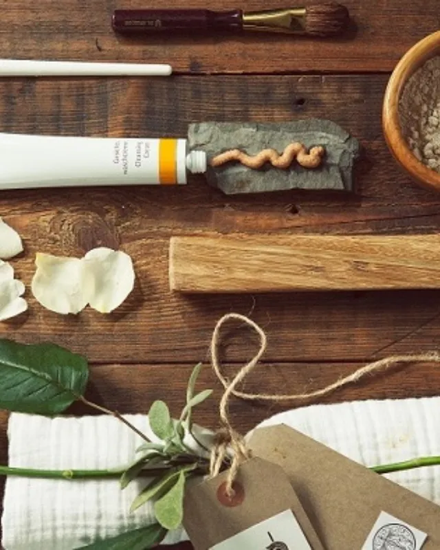Skincare items, white roses, and petals on a wooden surface.